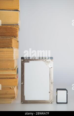 Stack of books, hard disk drive and memory card. Storage data, compressed information, digital versus analog concept Stock Photo