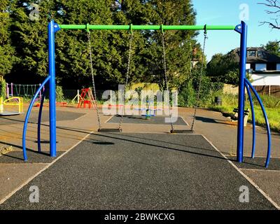 Colourful children's swings and play equipment in local municipal park Stock Photo