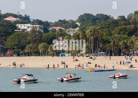 Sand beach on Gulangyu Island. With motorboats & tourists. In the background residential buildings. The whole island is an UNESCO World Heritage Site Stock Photo