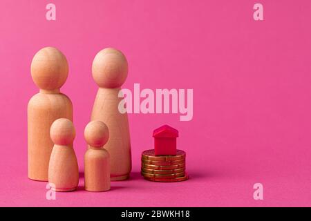 Wooden family with toy house and stack of coins. Savings for house purchase concept Stock Photo