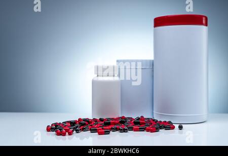 Antibiotic capsule pills spread on white table and plastic drug bottle white blank label. Antibiotic drug resistance. Pharmaceutical manufacturing Stock Photo