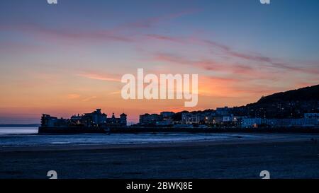 Sunset casts a red sky behind Knightstone Island and Worlebury Hill on the seafront of Weston-super-Mare. Stock Photo