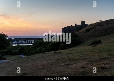 Weston-Super-Mare, England, UK - May 31, 2020: A couple walk on the hillside of Uphill Beacon beside St Nicholas Old Church in Weston-Super-Mare. Stock Photo