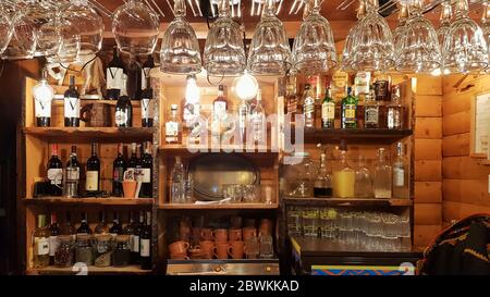 Ukraine, Kiev - June 2, 2020: Empty wine glasses over a wooden bar counter in a vintage rustic style. in the background a lot of different alcoholic d Stock Photo