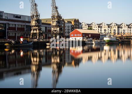 Bristol, England, UK - May 25, 2020: Morning light shines on dock cranes, warehouses, historic boats, and modern apartment buildings on Bristol's post Stock Photo