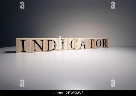 Indicator word from wooden blocks. Business and banking concept. Spot light on white background. Close up. Stock Photo