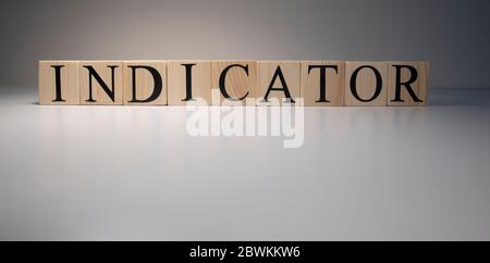 Indicator word from wooden blocks. Business and banking concept. Spot light on white background. Close up. Stock Photo