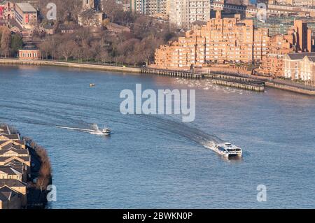 London, England, UK - February 27, 2015: A Thames Clipper ferry and speed boat travel along the River Thames past Wapping and Rotherhithe in East Lond Stock Photo