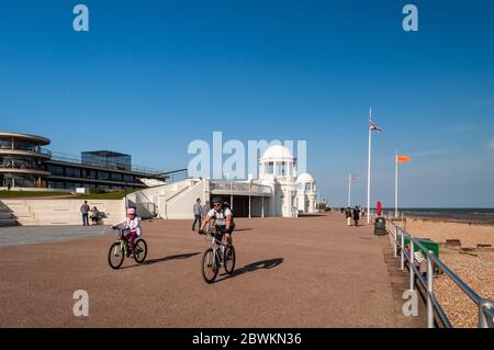 Bexhill on Sea, England, UK - June 8, 2013: People cycle and walk on the promenade outside the art deco De La Warr Pavilion on the seafront of Bexhill Stock Photo