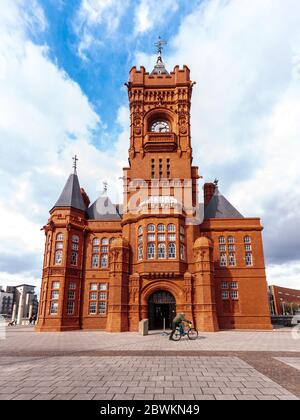 Cardiff, Wales, UK - March 17, 2013: A cyclist rides past the ornate Victorian Pierhead building in Cardiff Bay. Stock Photo