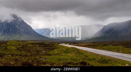Glencoe, Scotland, UK - June 4, 2011: Motorists and a cyclist cross the vast peat bog landscape of Rannoch Moor under the the mountains of Glen Coe in Stock Photo