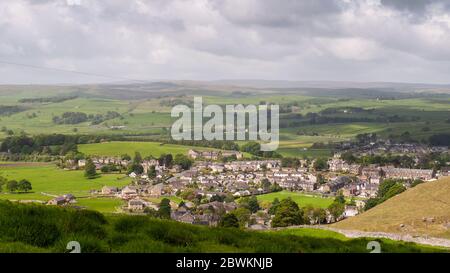 Sun shines on the houses of Settle town nestled in Ribblesdale valley under the hills of the Yorkshire Dales. Stock Photo