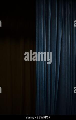 Dark blue velvet curtain on one side of a black theatre stage, vertical event background with large copy space Stock Photo