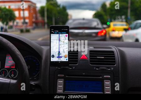 Driving and using waze maps application on smartphone on car dashboard, Driver using maps app for showing the right route through the traffic of city. Stock Photo