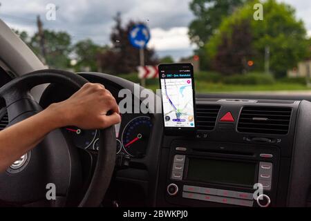 Driving and using waze maps application on smartphone on car dashboard, Driver using maps app for showing the right route through the traffic of city. Stock Photo