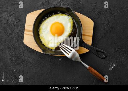 Fried egg in a small skillet with a stand, a bunch of dill, a jar of  peppercorns and whole white eggs on a brown wooden table Stock Photo - Alamy