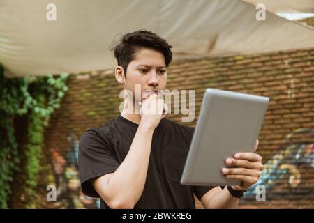 Serious young man using a tablet pc for work outdoor Stock Photo