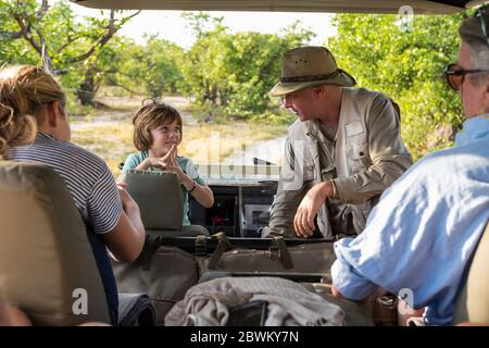 A family of visitors in a safari vehicle with a guide. Stock Photo