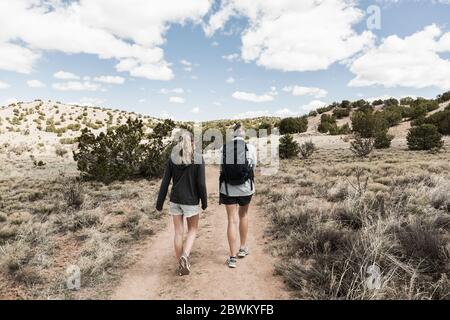 rear view of adult woman and her teenage daughter hiking in the Galisteo Basin, NM. Stock Photo