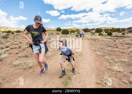 6 year old boy running on hiking trail with older sister, Galisteo Basin, NM. Stock Photo