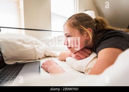 teen age girl looking at laptop in bed Stock Photo
