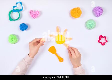 Girl playing playfoam at home isolated on white background. Top view. Home Education game with clay. Early development concept. Hands play with modeli Stock Photo