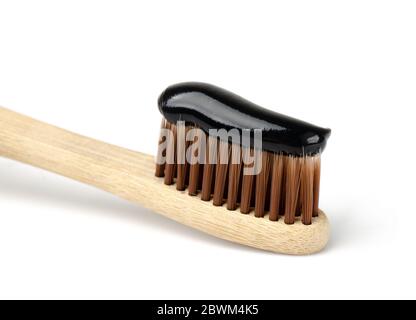 Bamboo toothbrush with black charcoal toothpaste. Close up of black toothpaste on toothbrush. Stock Photo