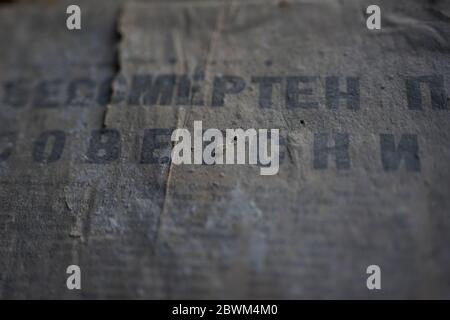 Old dirty torn dusty crumpled unreadable russian newspaper, translation: "Immortal Soviet". Stock Photo