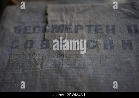 Old dirty torn dusty crumpled unreadable russian newspaper, translation: "Immortal Soviet". Stock Photo