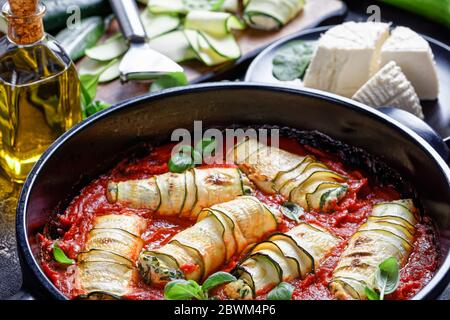 Zucchini lasagna rolls stuffed with ricotta mix of fresh baby spinach,  basil baked in tomato sauce served on a round black baking dish, fresh ricotta Stock Photo