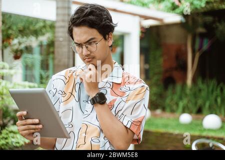Serious bespectacled man using a tablet pc for work outdoor Stock Photo