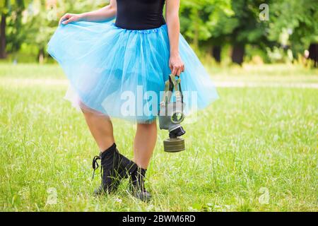 Woman in blue skirt with gas mask standing on green grass in a park. Environmental protection, biohazard and ecological concept Stock Photo