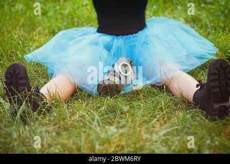 Woman in blue skirt with gas mask sits on green grass. Environmental protection, biohazard and ecological concept Stock Photo
