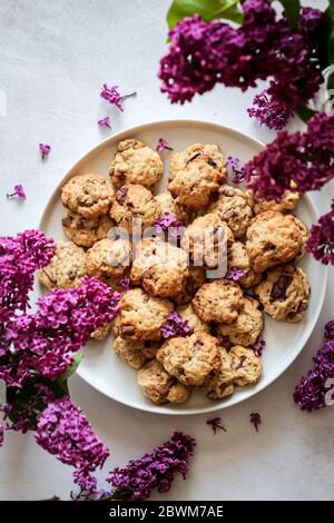 Chocolate chip cookies and purple lilac blooms shot from above Stock Photo