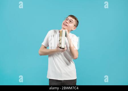 nerd holding books in his hands and smiling looking up Stock Photo