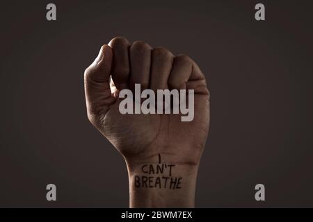 closeup of the raised fist of a man with the text I cant breathe in his wrist, as it is used as slogan in the George Floyd protests in response to pol Stock Photo