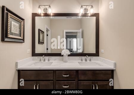 A small bathroom with a dark vanity and cream colored granite counter top. Stock Photo