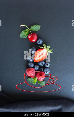 Summer fruits, berries and mint in chalk painted cup of tea on black background. Conceptual healthy, vitamin, dietary food. Vegan, vegetarian and detox food and drinks. Menu mock up for cafe, poster concept