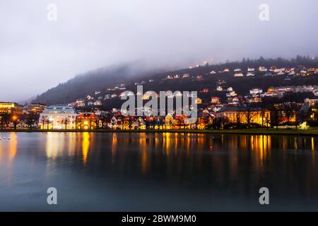Bergen, Norway. View of old town in Bergen, Norway in the evening. Famous landmarks with pond at night. Clouds over mountains Stock Photo