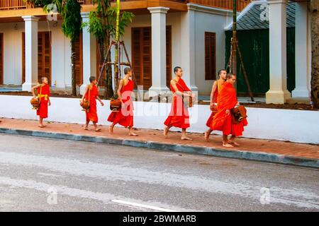 LUANG PRABANG, LAOS - JULY 27, 2016: Alms giving in the morning when monks walk by the streets for the food. Young monks in Luang Prabang, Laos Stock Photo