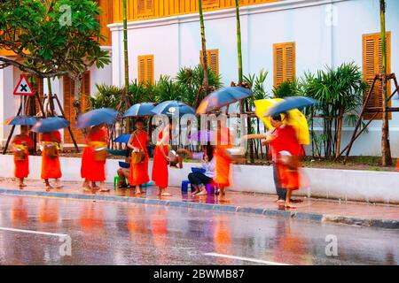LUANG PRABANG, LAOS - JULY 27, 2016: Alms giving in the morning when monks walk by the streets for the food. Young monks in Luang Prabang, Laos Stock Photo