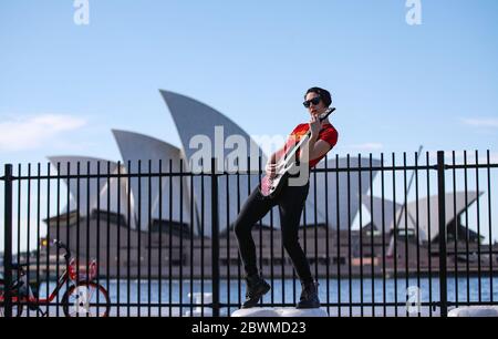 (200602) -- BEIJING, June 2, 2020 (Xinhua) -- A young woman performs guitar near the Sydney Opera House in Sydney, Australia, May 20, 2020. (Xinhua/Bai Xuefei) Stock Photo