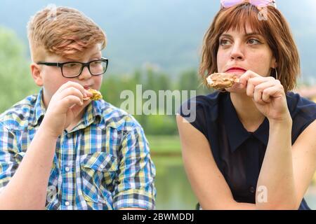 A young red-haired woman and a boy eating ice cream in a city on a hilly background.Young friends eat ice cream in a park. Stock Photo