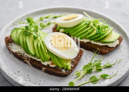 Avocado Sandwich with boiled Egg - sliced avocado and egg on rye toasted bread for healthy breakfast or snack Stock Photo