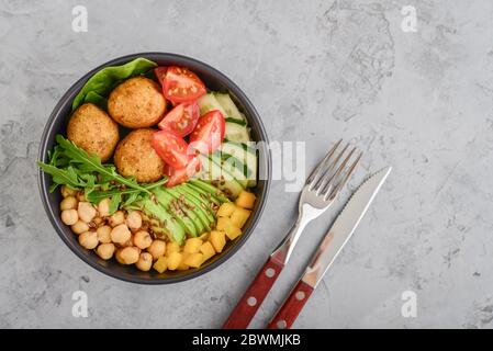 Vegetarian buddha bowl with cucumber, avocado, falafel, tomato and chickpeas on grey background, top view Stock Photo