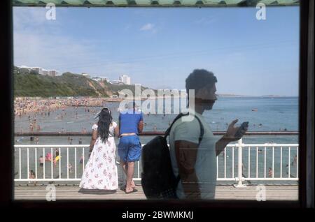 People walk along the pier in Bournemouth, Dorset, as the public are being reminded to practice social distancing following the relaxation of the coronavirus lockdown restrictions in England. Stock Photo