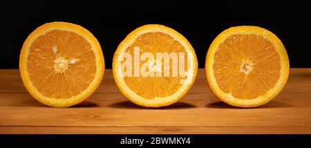 oranges on a wooden table, chopped oranges, three halves of oranges Stock Photo
