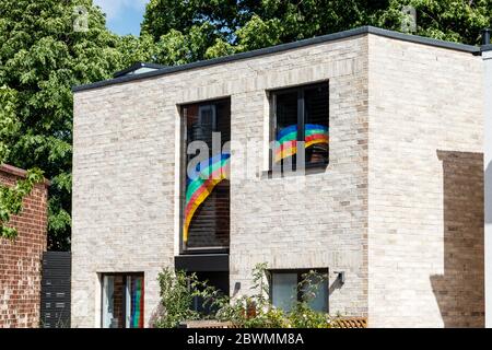 A modern house displaying a painted rainbow in its  windows in support of essential workers during the coronavirus health crisis, North London, UK Stock Photo