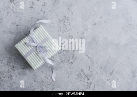 One striped gift box with grey ribbon on concrete background, top view Stock Photo