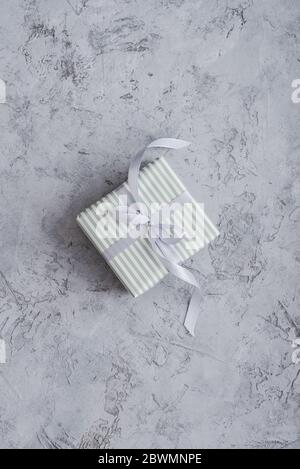 One striped gift box with grey ribbon on concrete background, top view Stock Photo